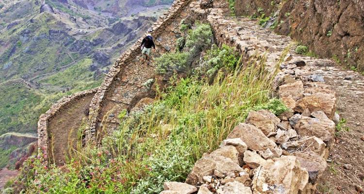 Personne faisant de la randonnée sur un sentier rocheux dans une région montagneuse.