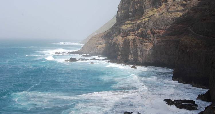 Côte escarpée avec de grandes vagues qui se brisent contre les rochers.