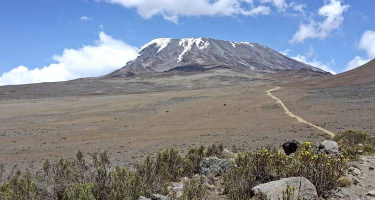 Vista amplia de una montaña cubierta de nieve y primer plano rocoso.