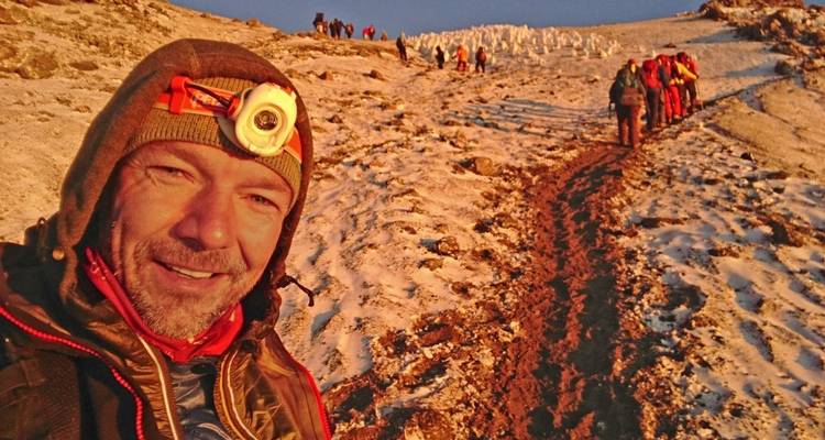 Un grimpeur prenant un selfie avec un groupe de randonneurs en arrière-plan.