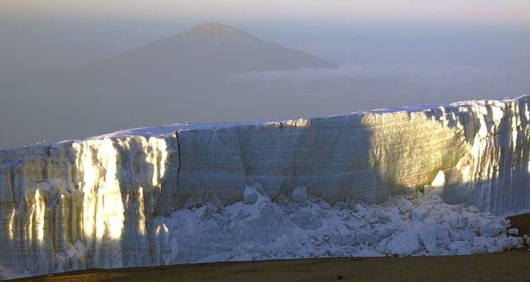 Un grand glacier avec une montagne visible au loin.