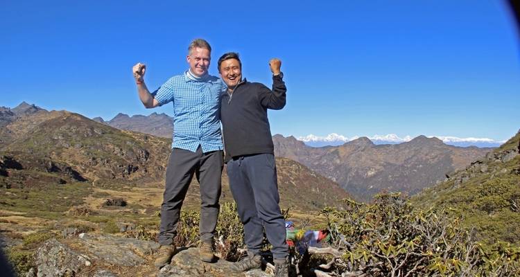 Two men posing triumphantly on a mountain summit.