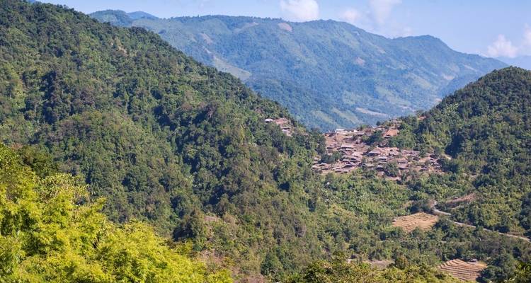 Ein ländliches Dorf, eingebettet in grüne Hügel, die in der Ferne sichtbar sind.