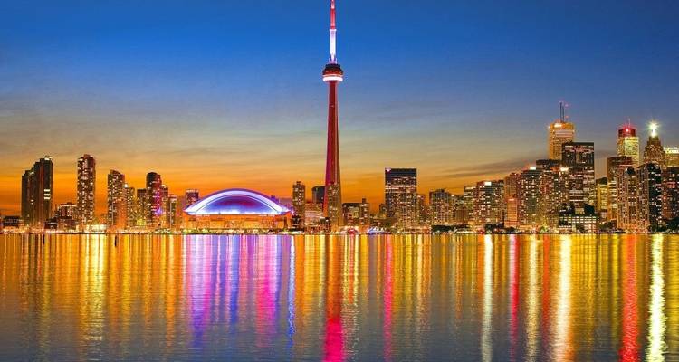 Horizonte de Toronto con la Torre CN y el paisaje urbano iluminado reflejándose en el agua.