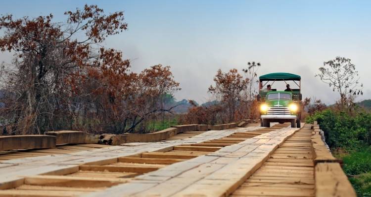 Camión cruzando un puente de madera en una zona rural.