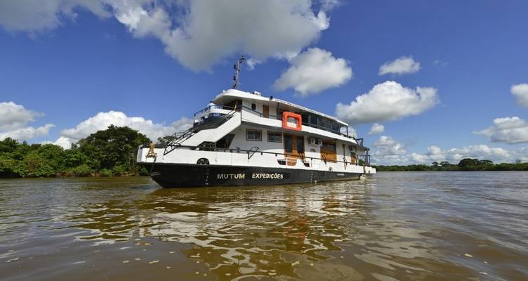 Un barco fluvial llamado Mutum Expedições flotando en un río.