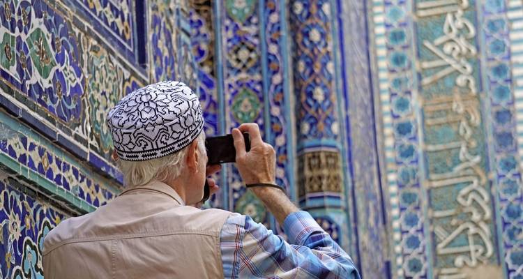 Bejaarde man fotografeert een blauw betegeld gebouw.