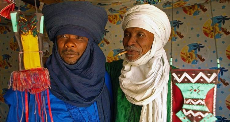 Deux hommes portant une tenue traditionnelle avec des décorations colorées.