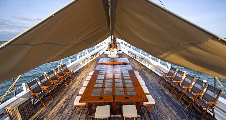 Lange tafel gedekt op het dek van een boot met uitzicht op de oceaan.
