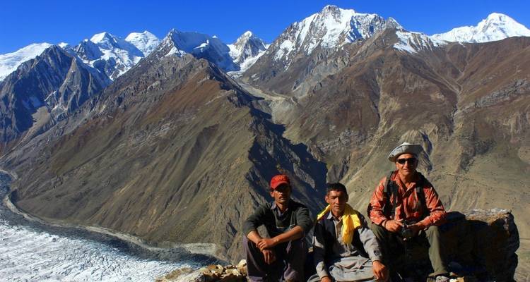 Drie mannen zitten op een berg met uitzicht op een gletsjer.