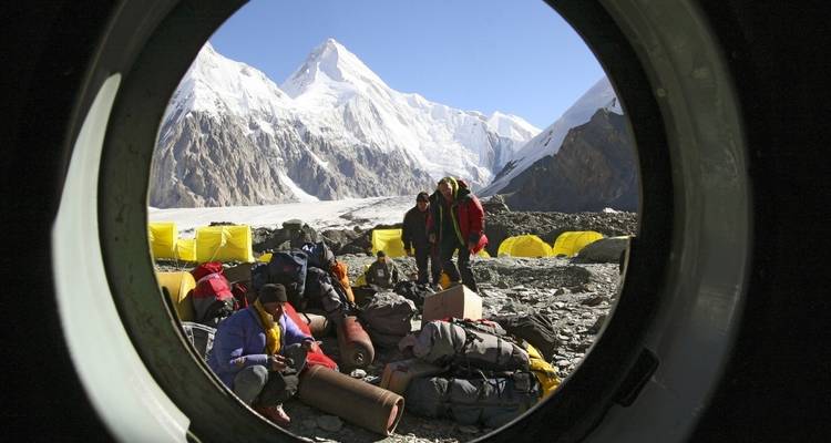 Campers setting up a base near snowy mountains.