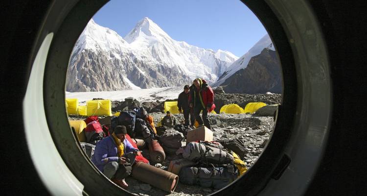 Covered in high-altitude gear, a group organizes at a mountain base camp.