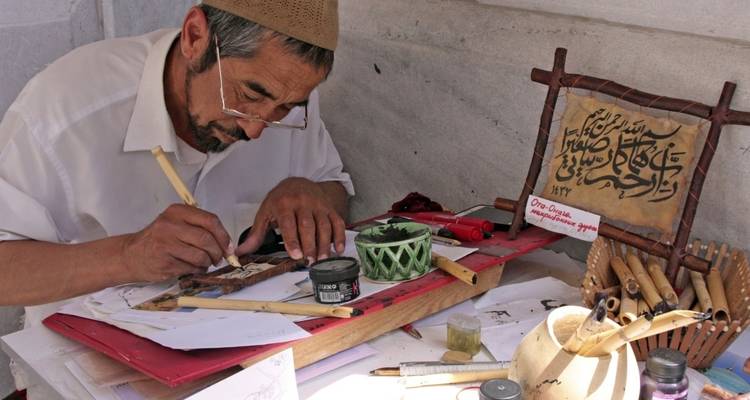 Ein Handwerker, der an traditioneller Kalligrafie mit Werkzeugen und Tinte arbeitet.