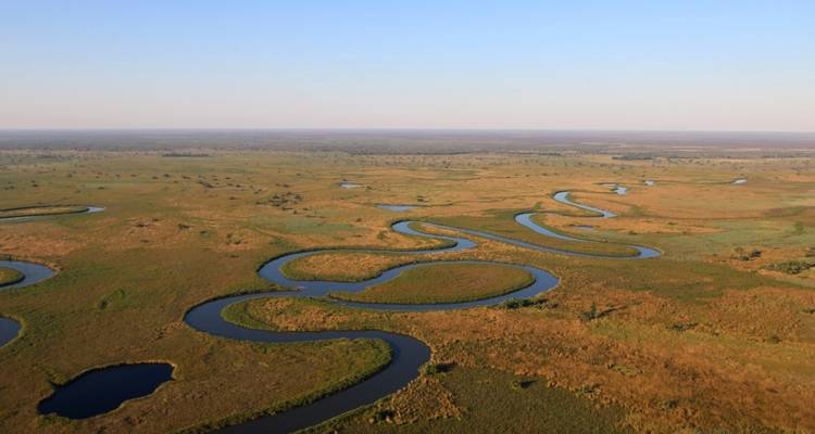 Aerial view of meandering rivers through a vast landscape of grassland.