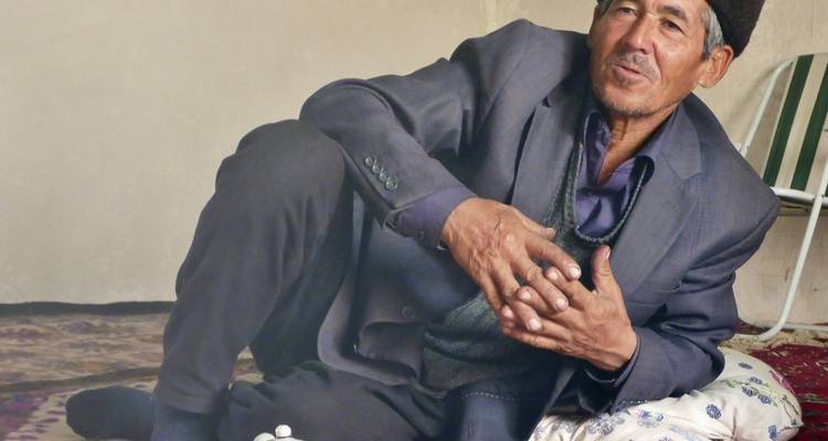 Homme en tenue traditionnelle assis confortablement à l'intérieur.