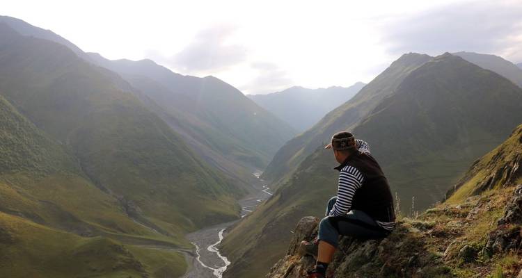 Personne assise au sommet d'une crête de montagne avec une vallée.