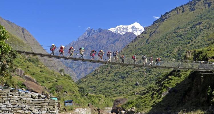 Group of trekkers crossing a suspension bridge in the mountains