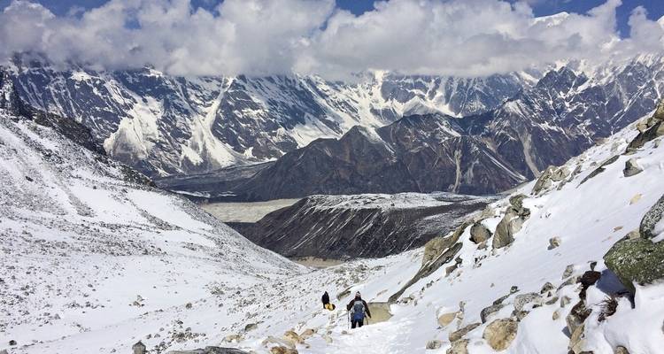 Hikers on a snowy mountain path with vast views