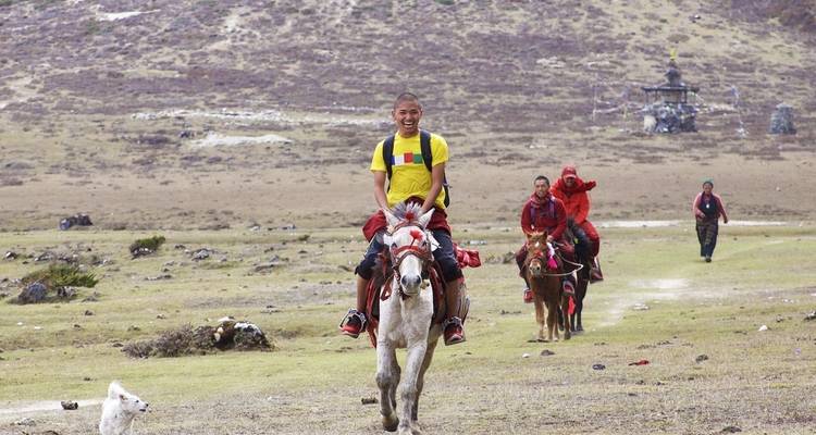 Smiling child riding a horse in a remote hilly area