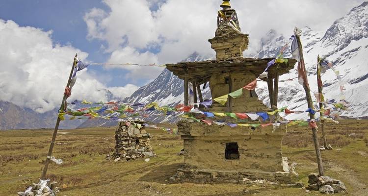 Stone monument with prayer flags at the foot of mountains