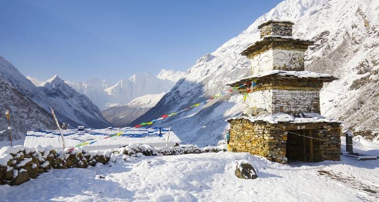 Stone stupa with prayer flags in snowy landscape