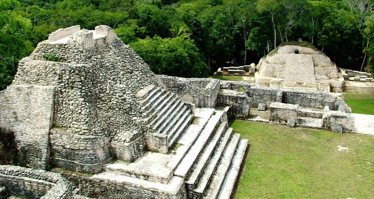 Ruinas de estructuras antiguas con escalones y área cubierta de hierba.