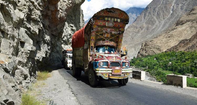Decorated truck on a mountainous road with dramatic scenery.