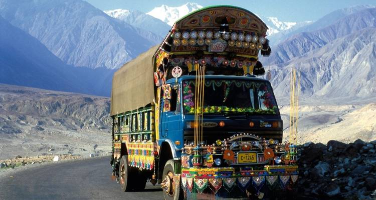 Ornately adorned truck on a scenic mountain road with clear skies.