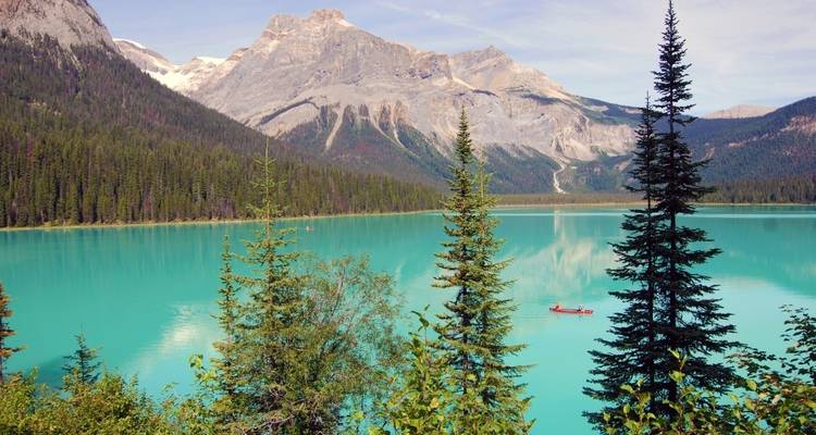 Lac turquoise entouré de montagnes et de forêt.