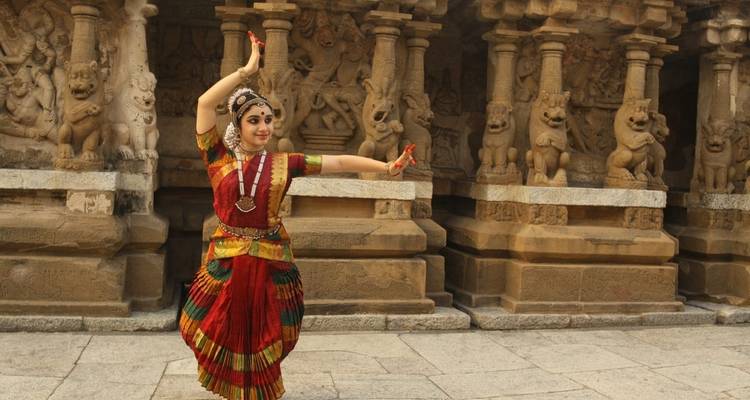 Traditionele danser die poseert voor een historische tempel.