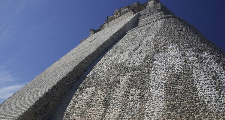 An upward view of a pyramid structure with a clear blue sky behind.