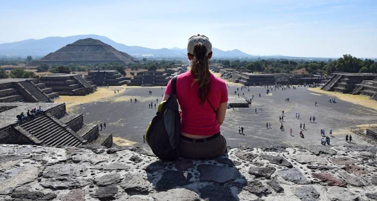 A woman sitting and admiring the view of the Teotihuacan pyramids.