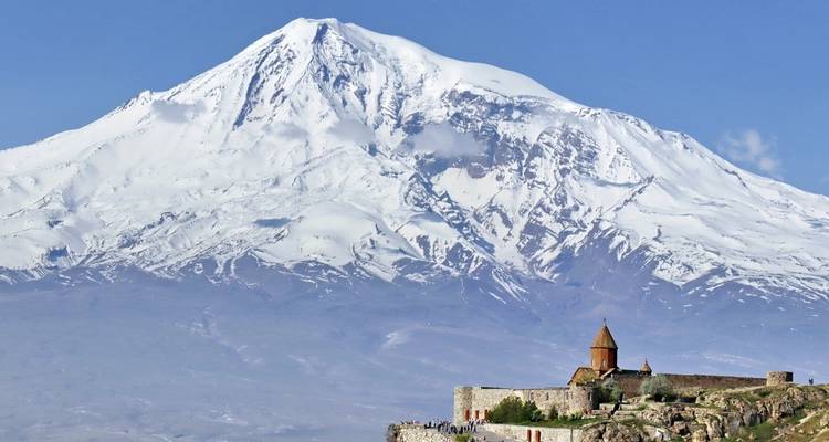 A historic church with a mountainous backdrop set amid grassland.