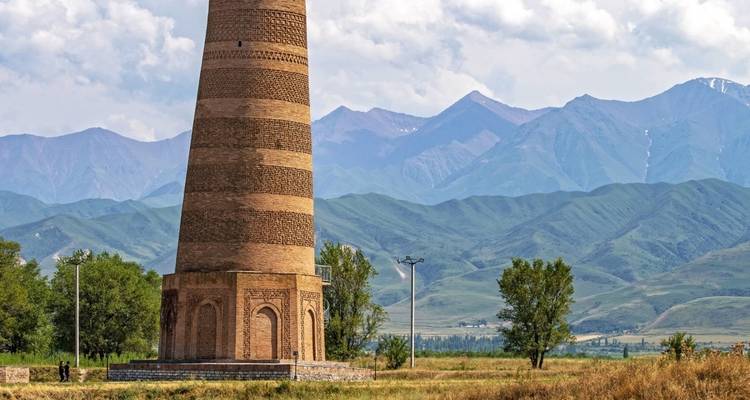 Ancient brick tower with mountains in the background.
