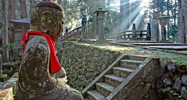 Statue de pierre dans une forêt avec des rayons de soleil filtrant à travers les arbres.