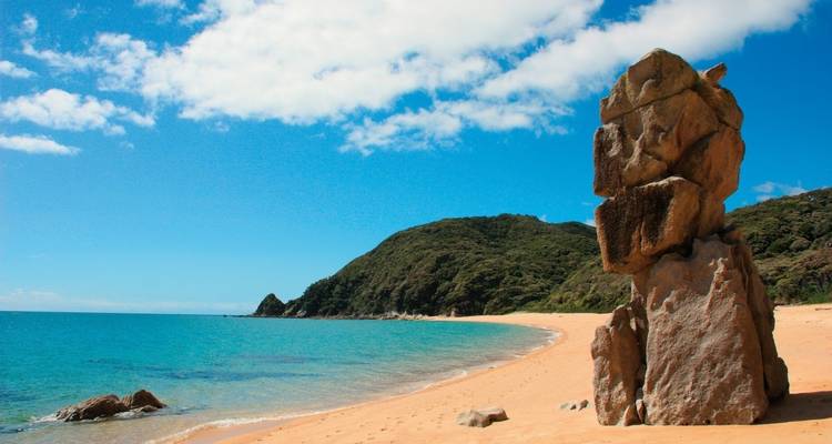 Schilderachtig strand met rotsformaties en turquoise water.