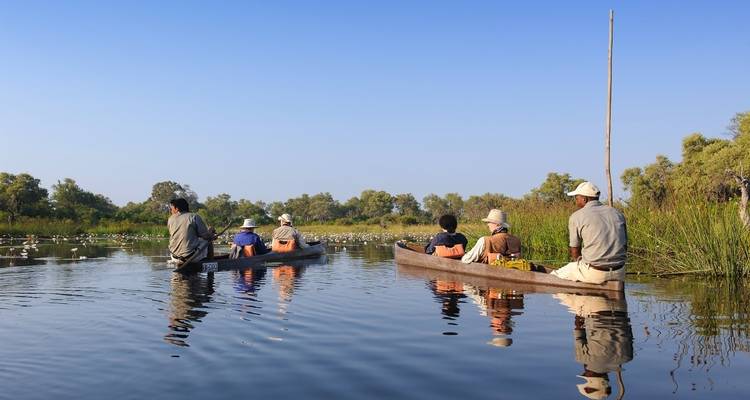 Dos canoas con personas en un río tranquilo.
