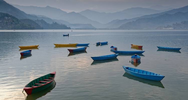 Colorful boats floating on a lake surrounded by mountains.