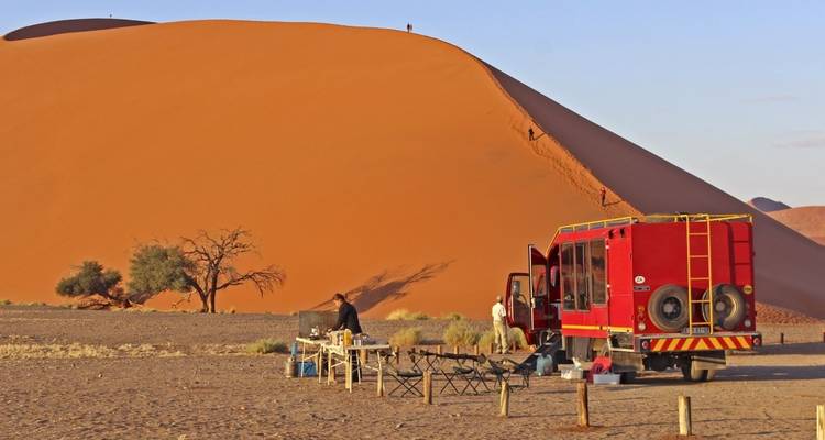 Group camping with a truck at a desert sand dune.