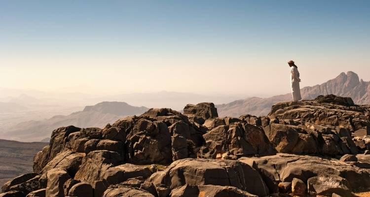Person standing on rocky mountain appreciating the view.