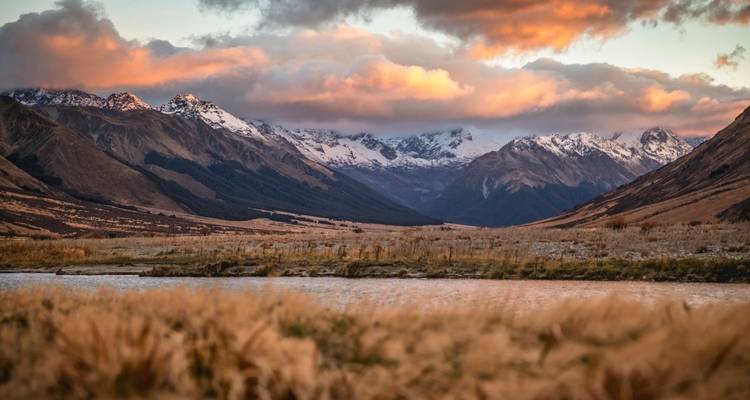 Un paysage de montagne serein avec une rivière et des nuages.