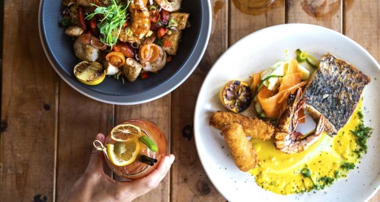 Une variété de plats gastronomiques sur une table en bois avec une boisson.