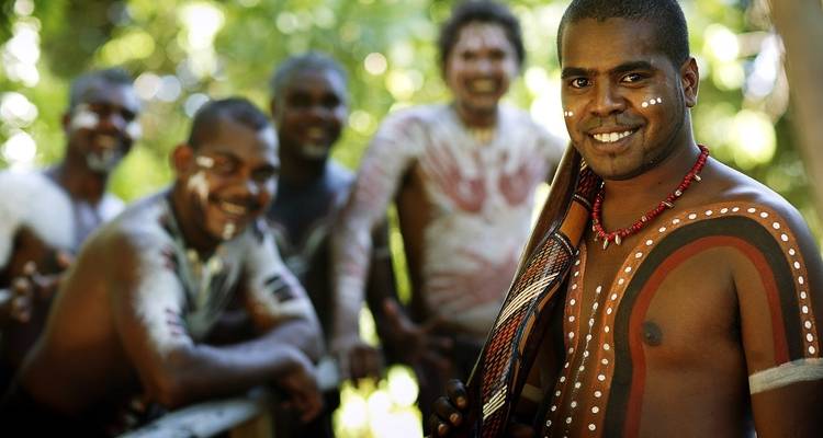 Un groupe d'hommes aborigènes d'Australie avec de la peinture corporelle, souriants.