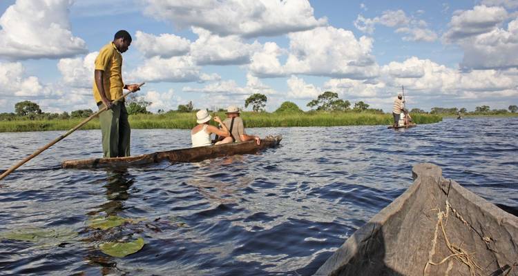 Tourists paddling in traditional boats on a waterway.