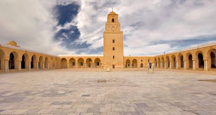 Courtyard of a mosque with a central minaret.