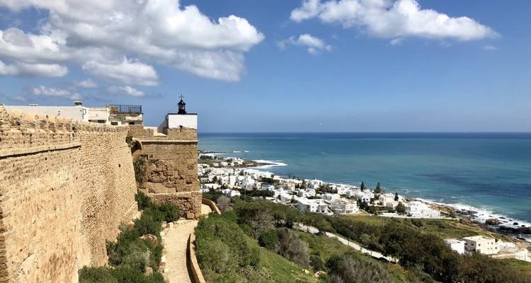 Coastal fortress with a view over a blue sea and town.