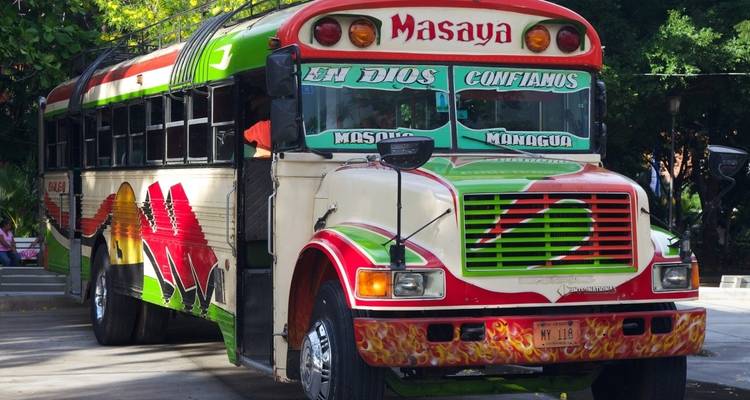 Ein bunter Bus mit dem Namen 'Masaya' darauf gemalt, geparkt auf einer Straße.