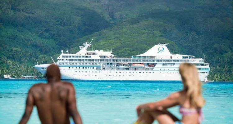 Un crucero de lujo anclado con personas observando desde la orilla.