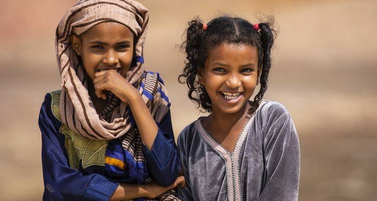 Two children smiling and wearing traditional clothing.
