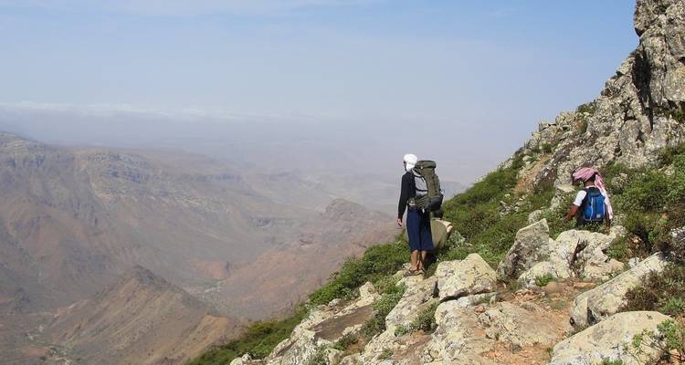 Hikers on a rocky mountain trail with panoramic views.